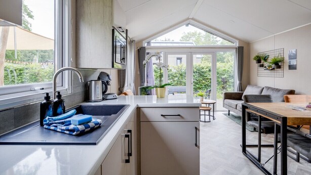 Una cocina moderna con un ventanal grande, una zona de comedor con mesa y sillas, y vistas al exterior.