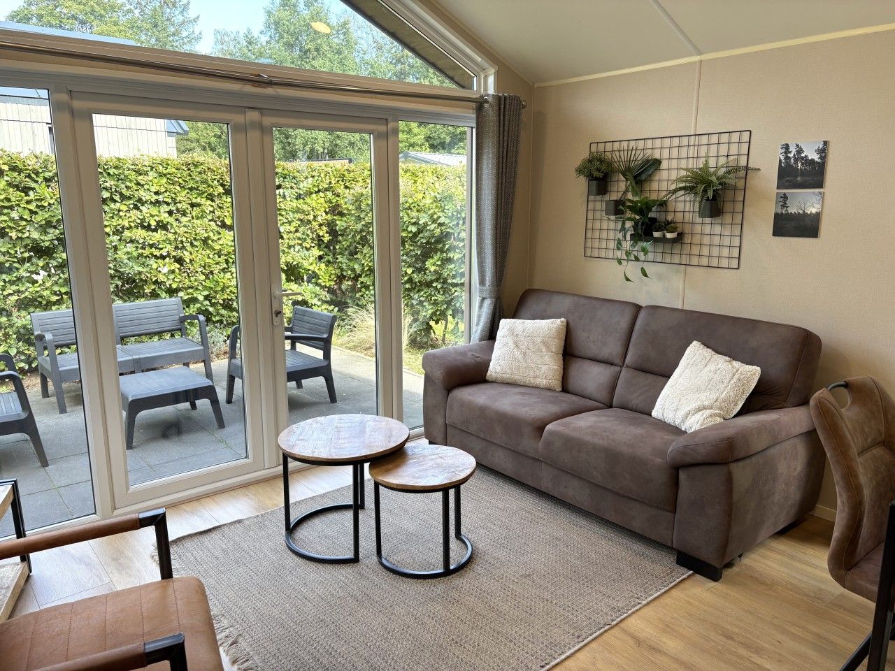 A living room with a sofa, two round tables, and a view through a glass door to an outdoor seating area.