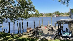 A lakeside dock with picnic tables and a small boat, surrounded by trees and a clear view of the water. - Waterfront Bayou living only 30 minutes from New Orleans, Dock Fishing (Lafitte)