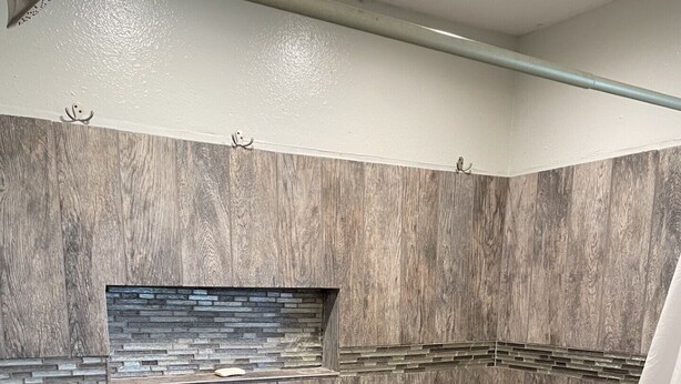 A shower area with a herringbone-patterned floor, a stone accent wall, and a metal showerhead. - Waterfront Bayou living only 30 minutes from New Orleans, Dock Fishing (Lafitte)
