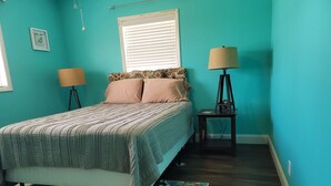 A bedroom with a bed, two bedside lamps, a window with blinds, a rug, and a wall-mounted picture. - Year Around View Lake Tenkiller (Vian)