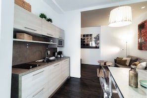 Een moderne keuken met een ingebouwde magnetron, een koffieapparaat en een bar met een glazen blad.