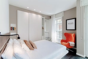 A bedroom with a bed, a wardrobe, a chair, and a framed picture on the wall. - Style Suite Apartment - My Home in Como (Como)