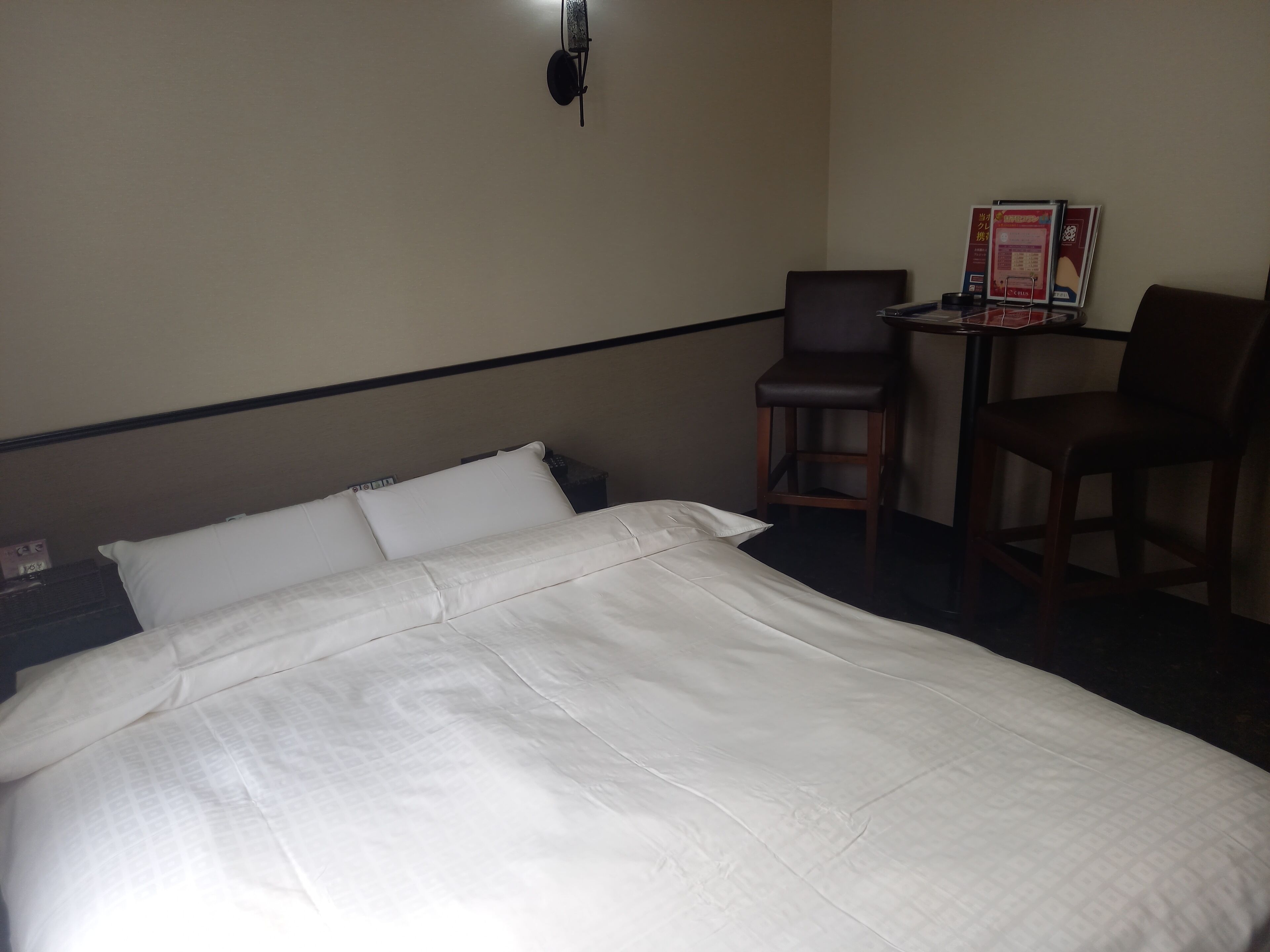 Ein Hotelzimmer mit einem Bett, zwei Stühlen, einem kleinen Tisch und einer Wandleuchte.