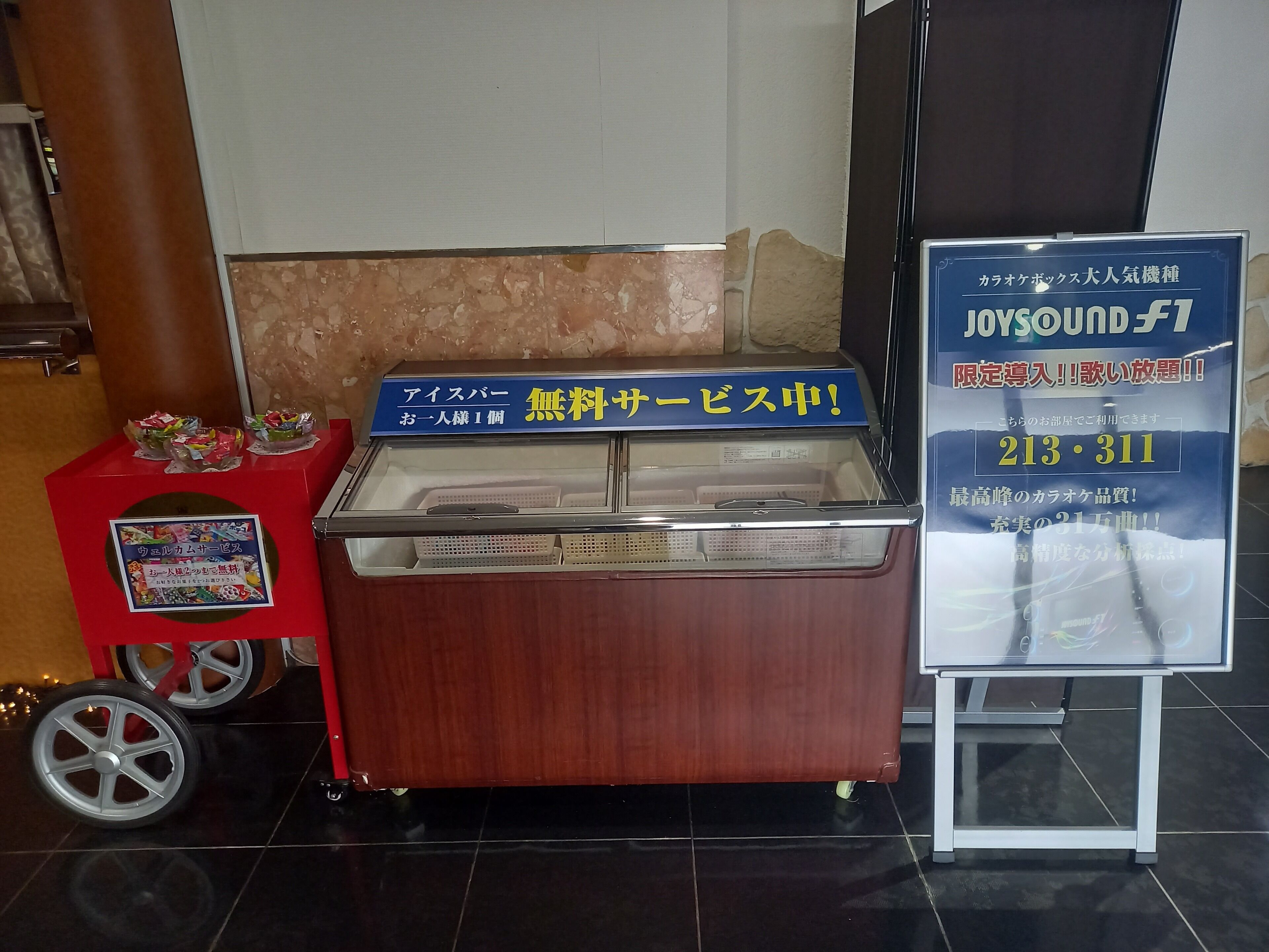 Zona de recepción con un mostrador de madera, un cartel y una vitrina con tapa azul.