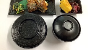 A black plate with a decorative lid, a rectangular plate with food, and a small dish with yellow and red items. - HOTEL C-PLUS - Adults Only (Gyoda)