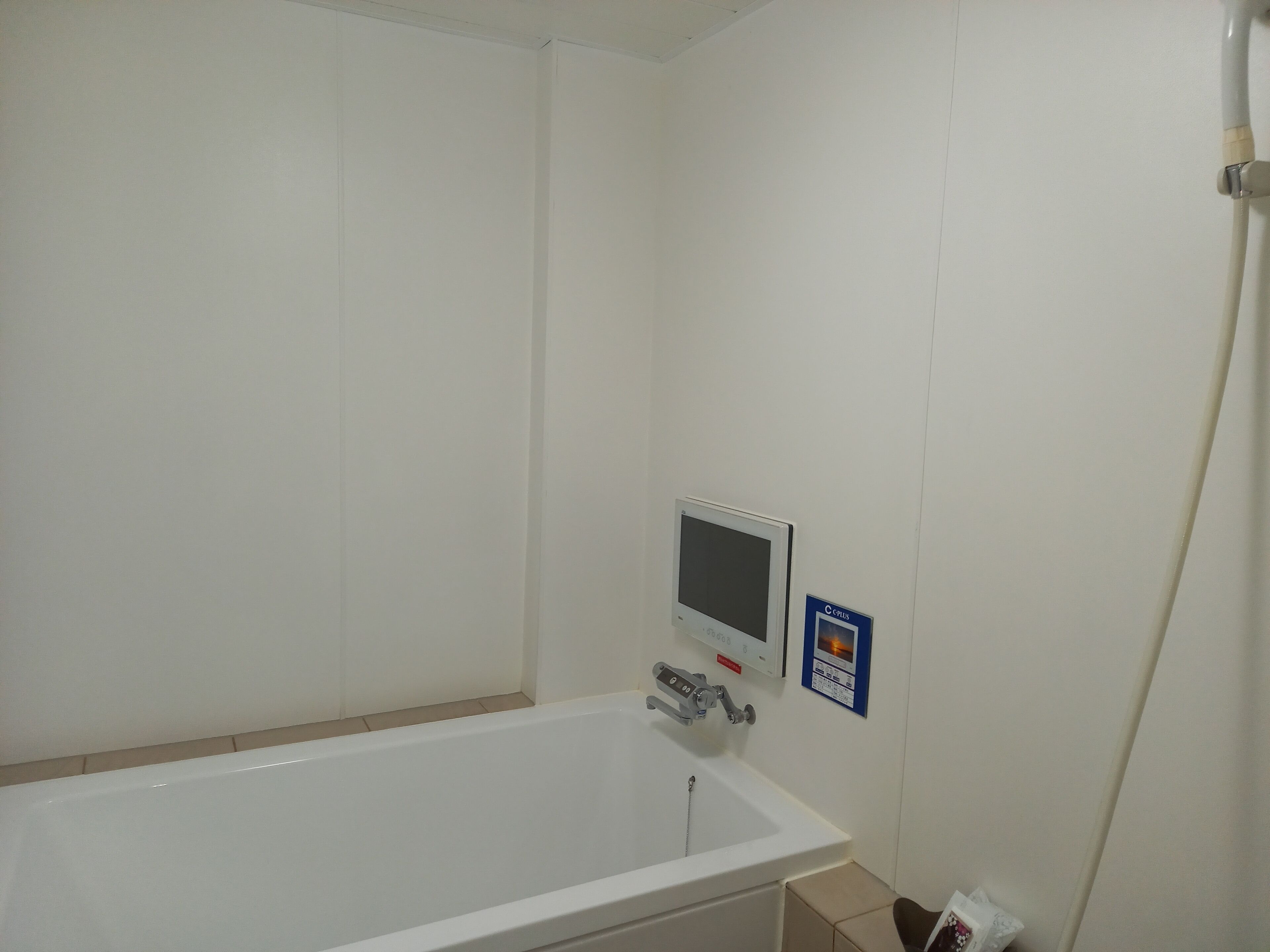 Un baño con una bañera blanca, un panel de control digital y un letrero que indica una instalación CP Plus.