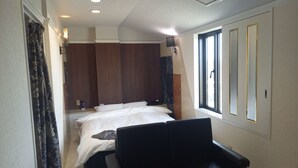 A hotel room with a bed, a seating area, a window, and a shower. - HOTEL C-PLUS - Adults Only (Gyoda)