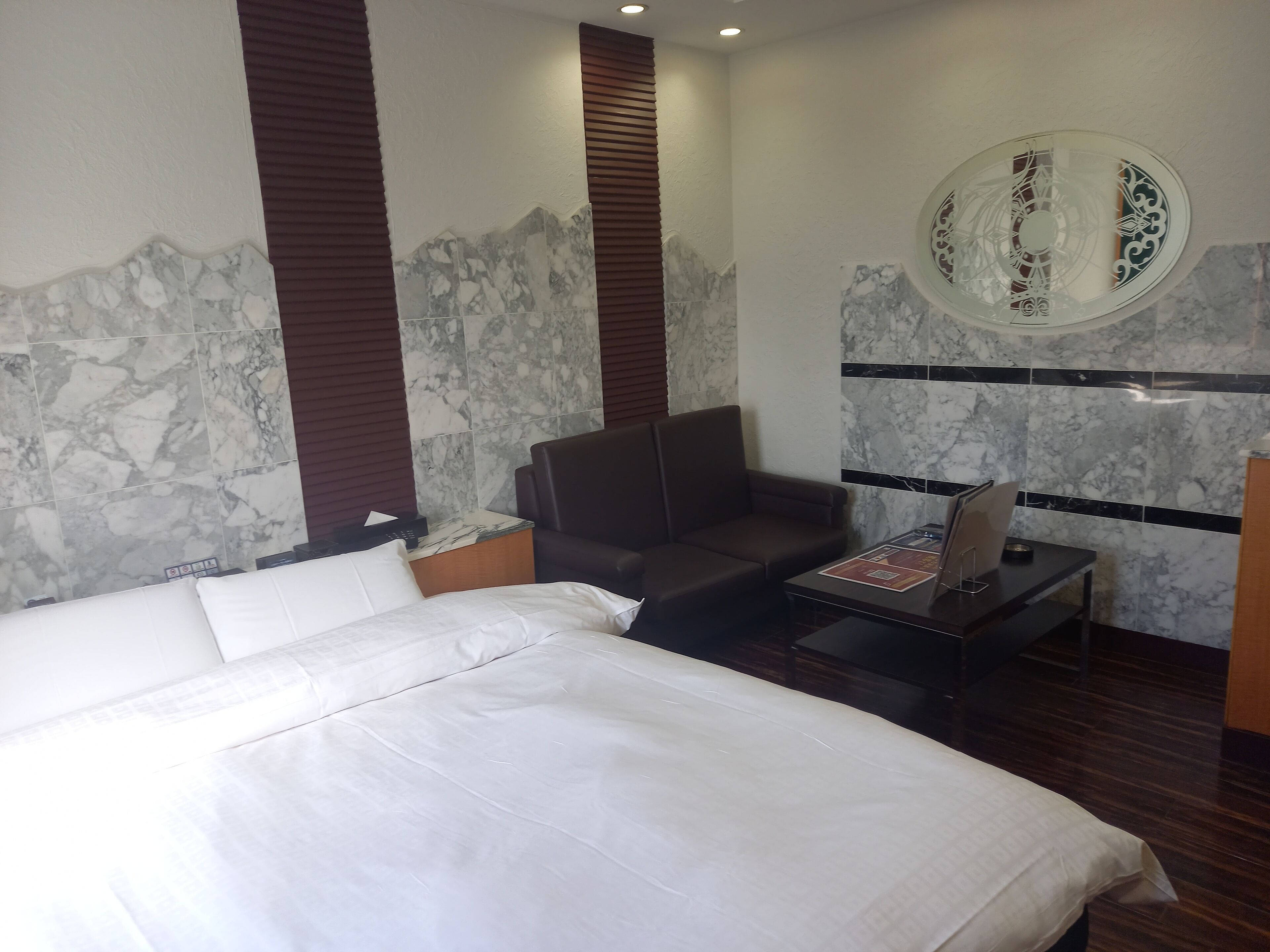 A hotel room with a large bed, a seating area, and a small table with a magazine.