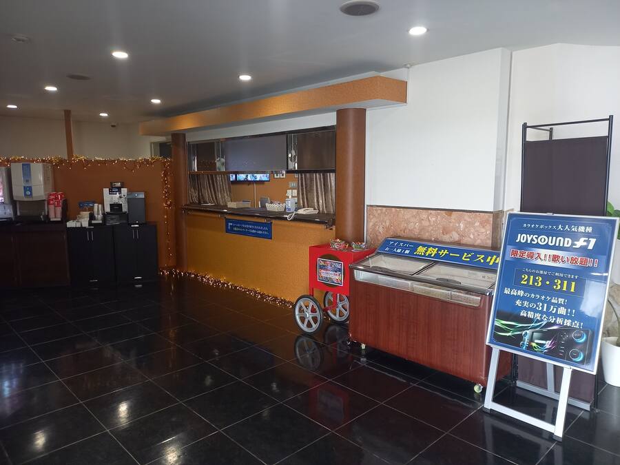 A hotel reception area with a counter, a coffee machine, and a signboard advertising a sound system.
