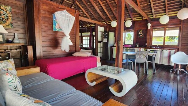 Une cabane en bois comprenant un lit, un canapé, un coin repas et une table.