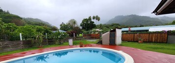 Una piscina con cubierta de madera, rodeada de vegetación exuberante y vistas a montañas.