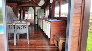 Un intérieur en bois comprenant un coin repas, une cuisine et une vue sur l’extérieur.