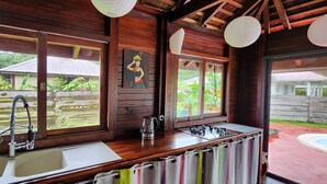 Une cabane en bois dotée d’un coin cuisine, comprenant un évier, une cuisinière et des fenêtres donnant sur un jardin.