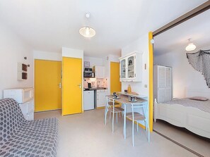 Um espaço compacto com cozinha compacta, área de refeições e cama.