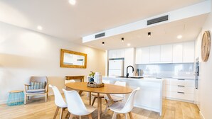 A modern kitchen with white cabinets, a wooden dining table, and white chairs.