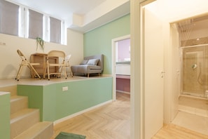 Un interior moderno con una escalera, un comedor con sillas, un sofá y un cuarto de ducha.