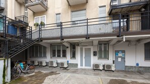 A building with a balcony, air conditioning units, a bicycle, and a door. - GuestHost - Insubria Park - Pastel Colored Apartment! (Milano)