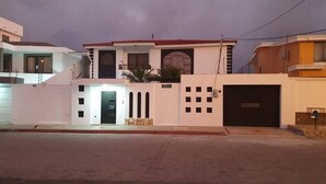 Un edificio de dos pisos con una entrada central, un garaje y un balcón pequeño.