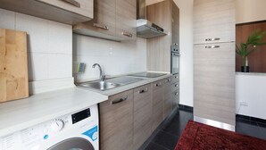 A modern kitchen with wooden cabinets, a stainless steel sink, and a built-in washing machine. - GuestHost - Corvetto M3 - Comfortable Apt. with balcony! (Milano)
