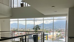 Um interior espaçoso com varanda e vista para a cidade e montanhas.