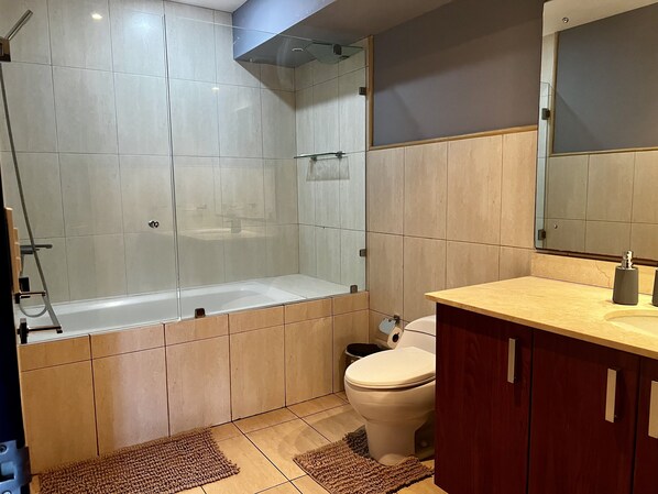Un baño moderno con ducha envuelta en vidrio, inodoro y tocador con espejo.