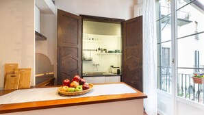 A kitchen with a wooden countertop, a fruit bowl, and a view of the balcony.