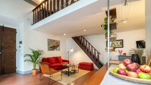 A spacious living area with a red sofa, a coffee table, a staircase, and a fruit basket.