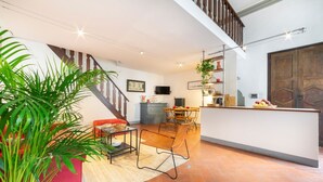 A spacious living area with a staircase, a dining area, and a kitchen with a bar.