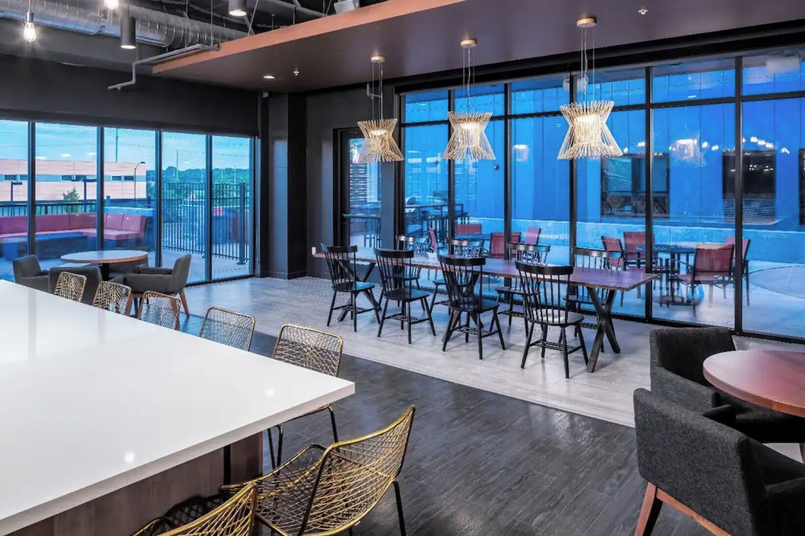 A modern dining area with large windows, a white table, and black chairs.