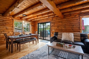 Ein rustikaler Innenraum einer Blockhütte mit Essbereich, einer Couch und einem Couchtisch.