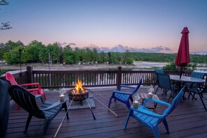 Eine Terrasse mit Feuerstelle, Sitzgelegenheiten im Freien und Blick auf einen Fluss.