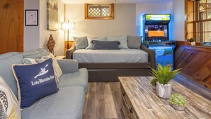 Une pièce confortable avec un canapé, un lit, une table en bois agrémentée de plantes et un téléviseur diffusant un événement sportif.