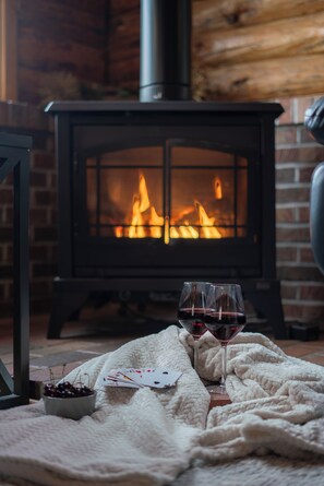 Una habitació acollidora amb una llar de foc, una manta i dues copes de vi negre.