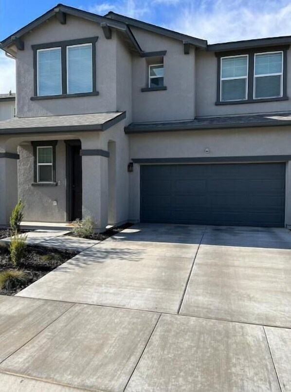A two-story house with a garage, a front door, and a driveway.