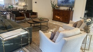 A modern living room with a sofa, armchairs, a coffee table, and a TV on a wooden cabinet.