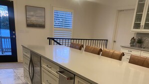 A kitchen with a large island, white cabinets, and a marble floor.