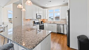 A modern kitchen with granite countertops, stainless steel appliances, and pendant lighting.