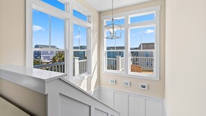 A staircase leading to a balcony with large windows overlooking a residential area.