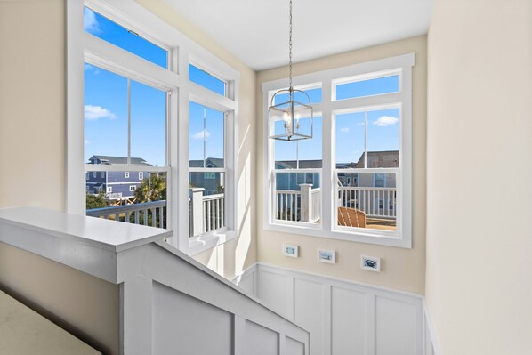 A staircase leading to a balcony with large windows overlooking a residential area.