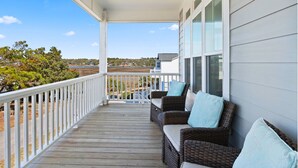 A covered porch with wicker furniture and a view of a residential area.