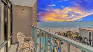 Ein Balkon mit Blick auf den Strand und das Meer bei Sonnenuntergang.