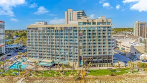A multi-story hotel with a pool area, surrounded by other buildings. - Sand Dunes 2745 (Myrtle Beach)