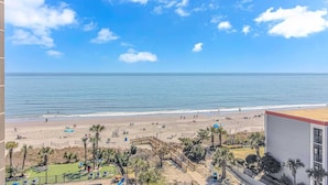 A beach view from a balcony with palm trees and a fenced area. - Sand Dunes 2745 (Myrtle Beach)