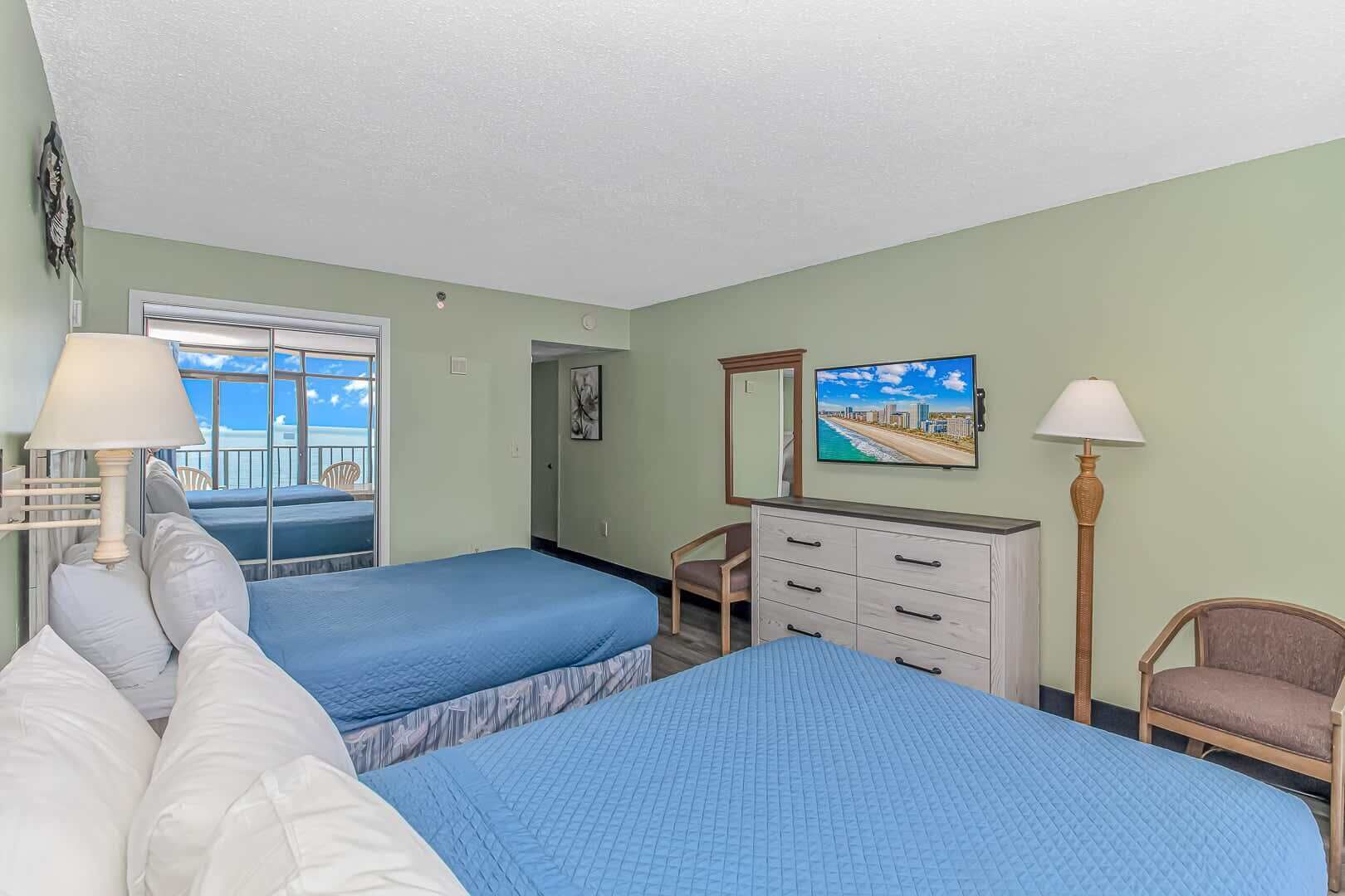 Een hotelkamer met twee bedden, een kaptafel, een stoel, een televisie en een raam met uitzicht.
