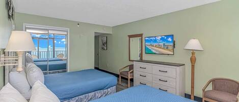 Een hotelkamer met twee bedden, een kaptafel, een stoel, een televisie en een raam met uitzicht.