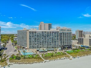 Un hotel moderno con varios pisos, una piscina y vista a la playa.