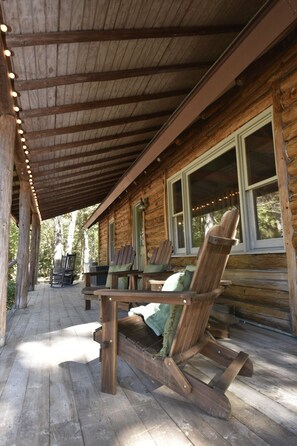 Une cabane en bois dotée d’un porche couvert, de fauteuils à bascule et d’une table.