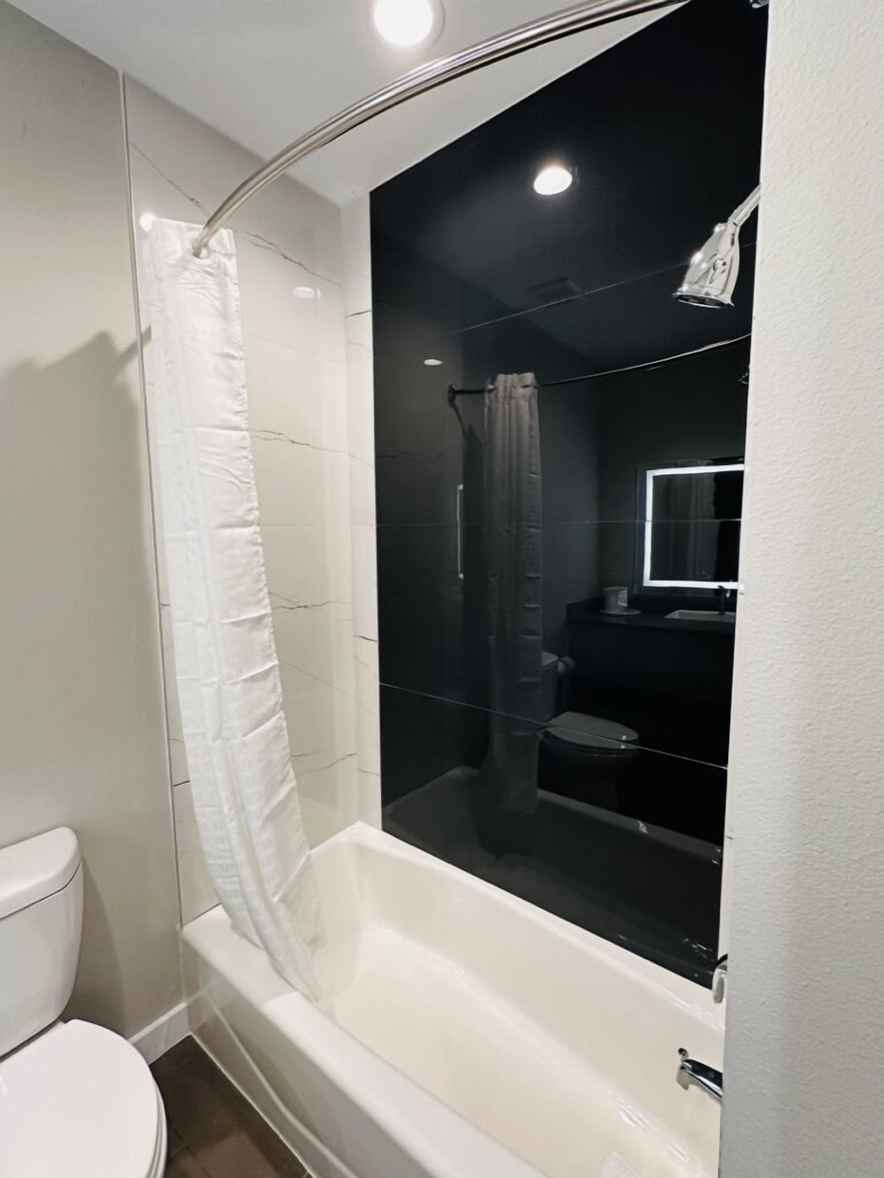 A modern bathroom with a glass-enclosed shower, white fixtures, and a visible toilet.