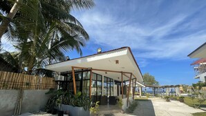 Una casa moderna con un porche cubierto, un camino de hormigón y vistas al mar.